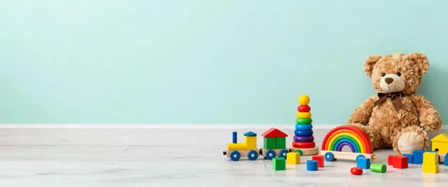 A teddy bear, wooden blocks, a train and stacking rings